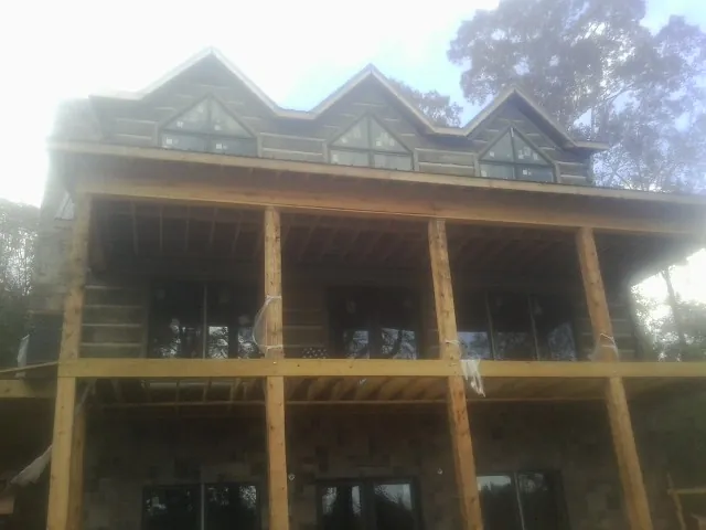 Dormers and porch framing on a large log home under construction — Roof Coating work by our crew in Conneaut Lake