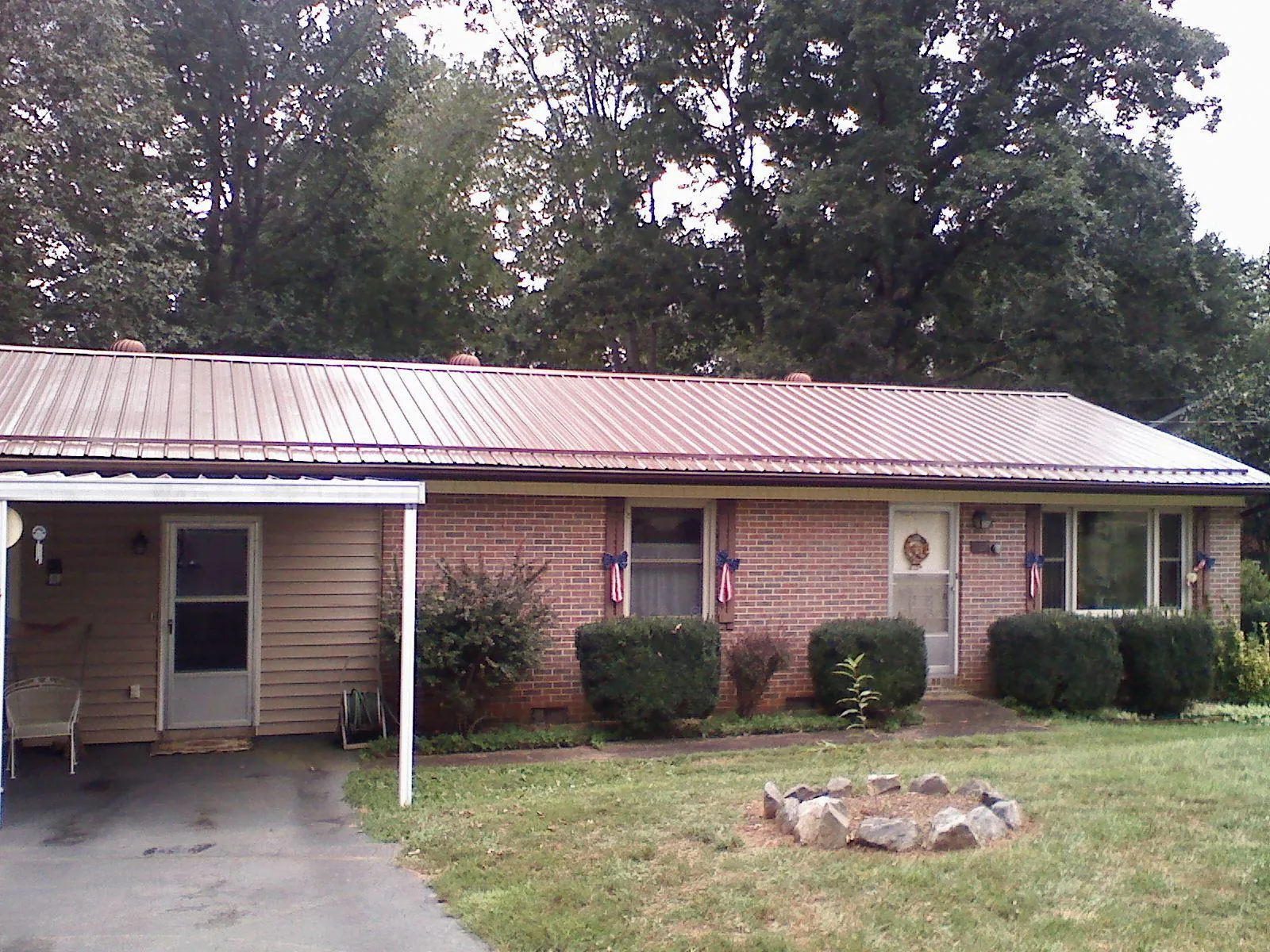 Bronze metal roof and carport on a brick ranch home — Roof Repair work by our crew in Conneaut Lake