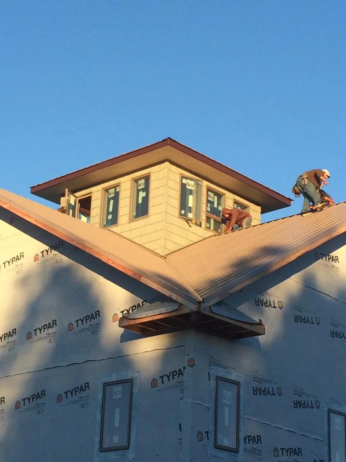 Roofers working around a rooftop cupola on a new metal roof at sunset — Roof Waterproofing in Conneaut Lake by Roofing Brothers